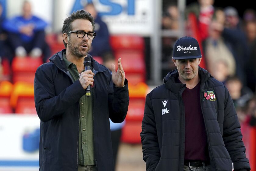 Wrexham owners Ryan Reynolds, left, and Rob McElhenney speak to the crowd before the National League match against Torquay United at the Racecourse Ground, Wrexham, Wales, Saturday Oct. 30, 2021. (Peter Byrne/PA via AP)