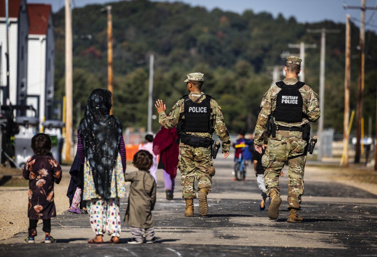 U.S. Military Police walk past Afghan refugees at the Village at the Ft. McCoy U.S. Army base