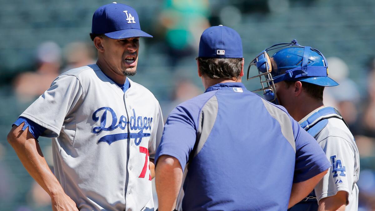Dodgers starter Carlos Frias, left, speaks with pitching coach Rick Honeycutt, center, and catcher Tim Federowicz during the first inning of the team's blowout loss to the Colorado Rockies on Wednesday.