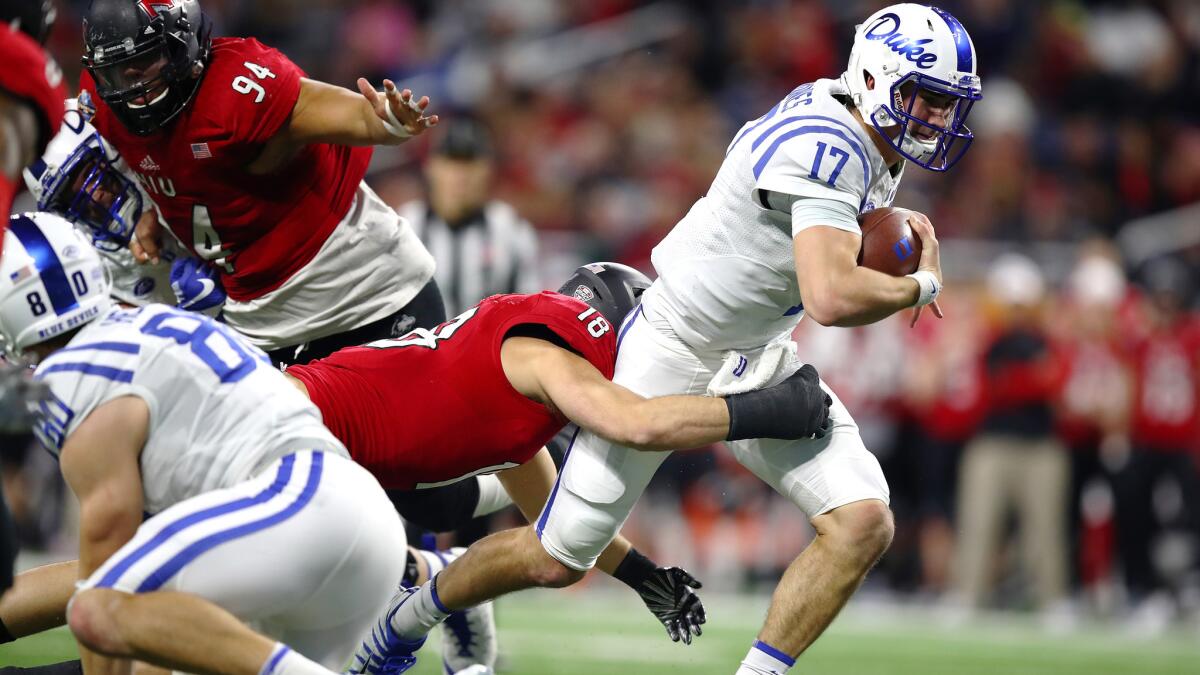 Duke quarterback Daniel Jones tries to break the tackle of Northern Illinois linebacker Alex Schwab during a run in the first half Tuesday night.