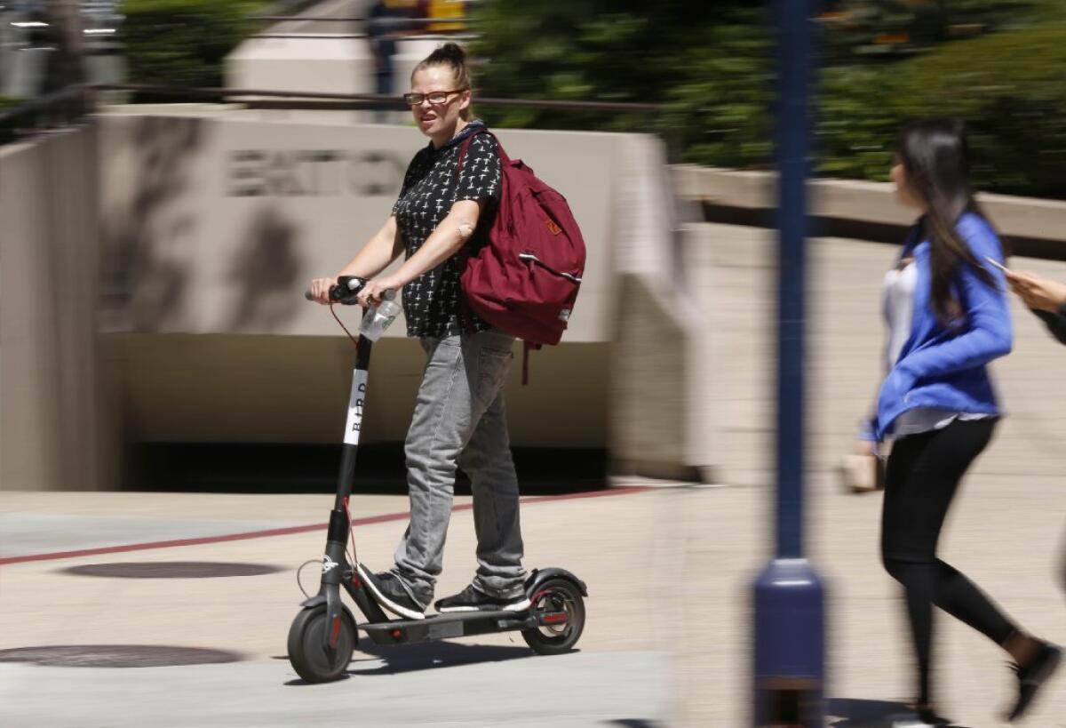SAN DIEGO, CA 9/14/2018: An electric scooter rider travels on the sidewalk of B Street near Sixth Avenue in downtown San Diego.