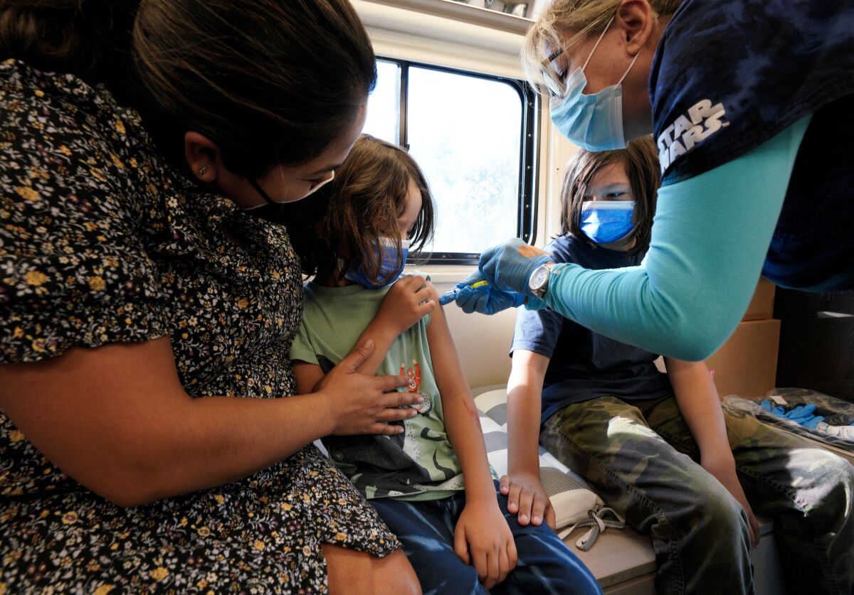 Julie Brown, with UC San Diego Health, vaccinated Beau Tafoya, 5, as his brother Luca,11 watched in the medical van. 