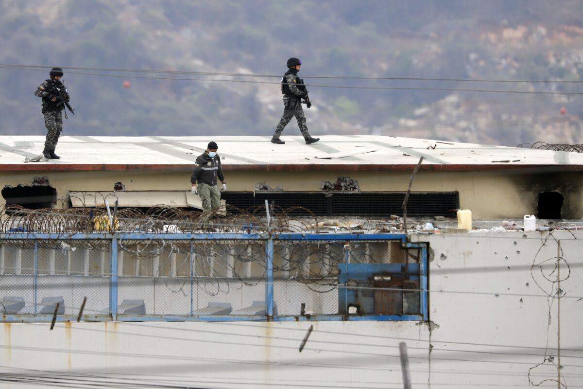 The body of a prisoner appears surrounded by police on the roof of the Litoral penitentiary the morning after riots broke out inside the jail in Guayaquil, Ecuador, Saturday, Nov. 13, 2021. (AP Photo/Jose Sanchez)
