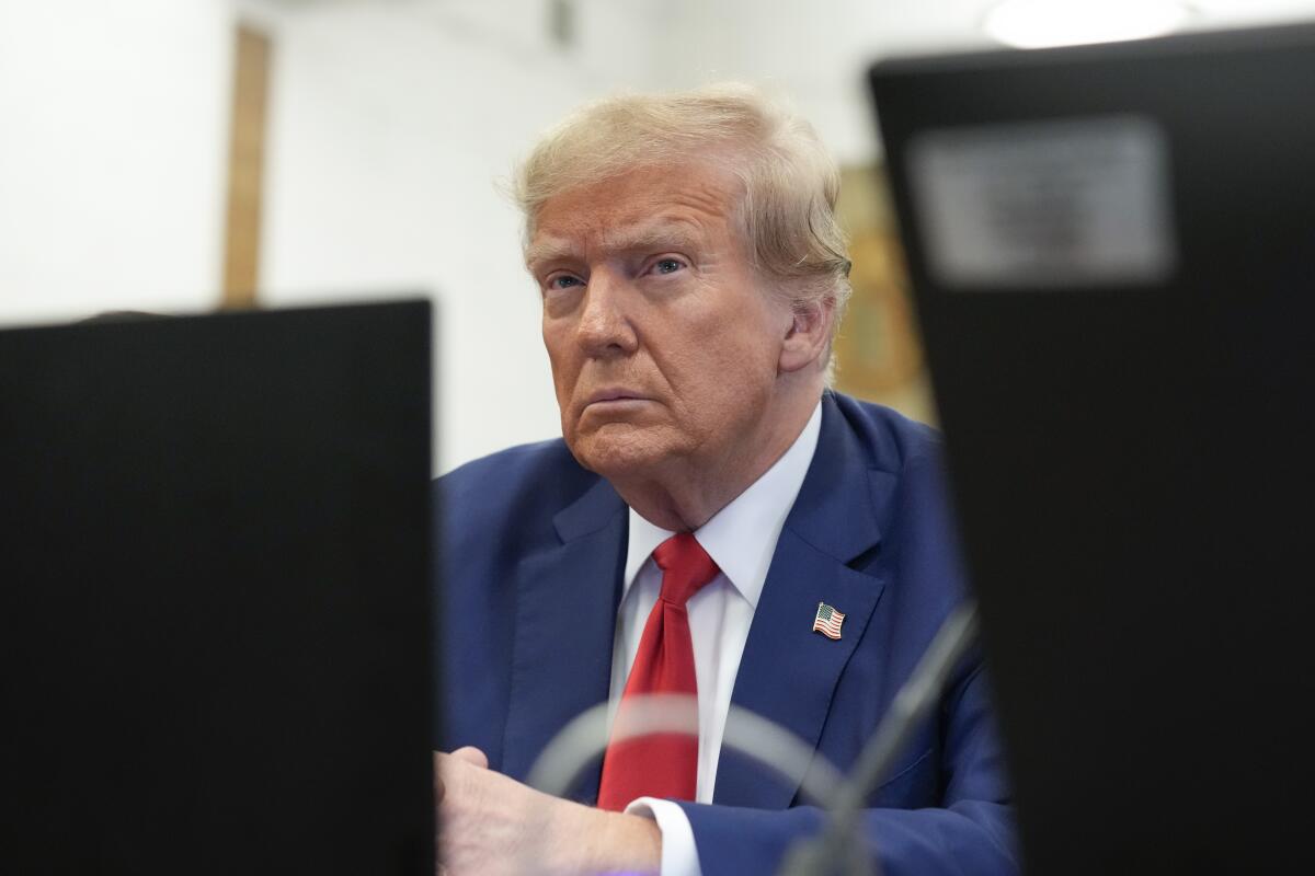 Framed by two computer screens, former President Trump sits in a courtroom.