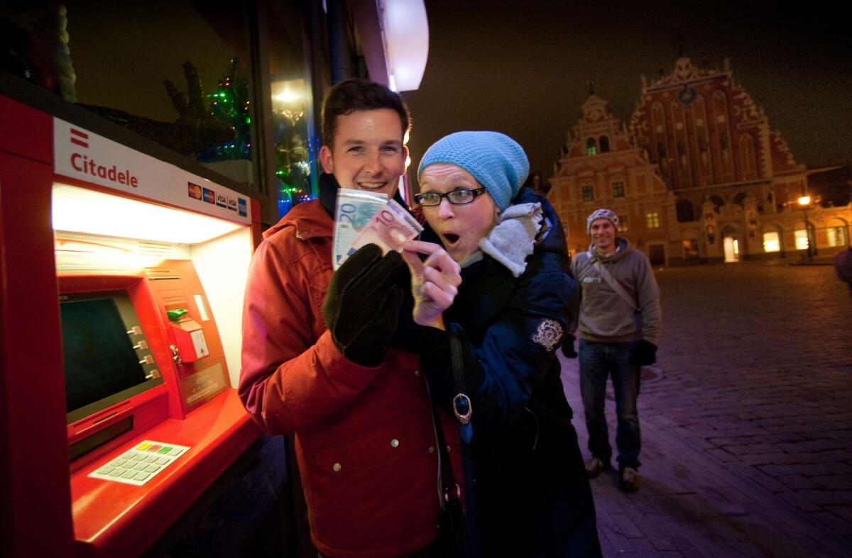 A young couple in Riga, Latvia, displays euro banknotes they withdrew Wednesday after the country entered the Eurozone.