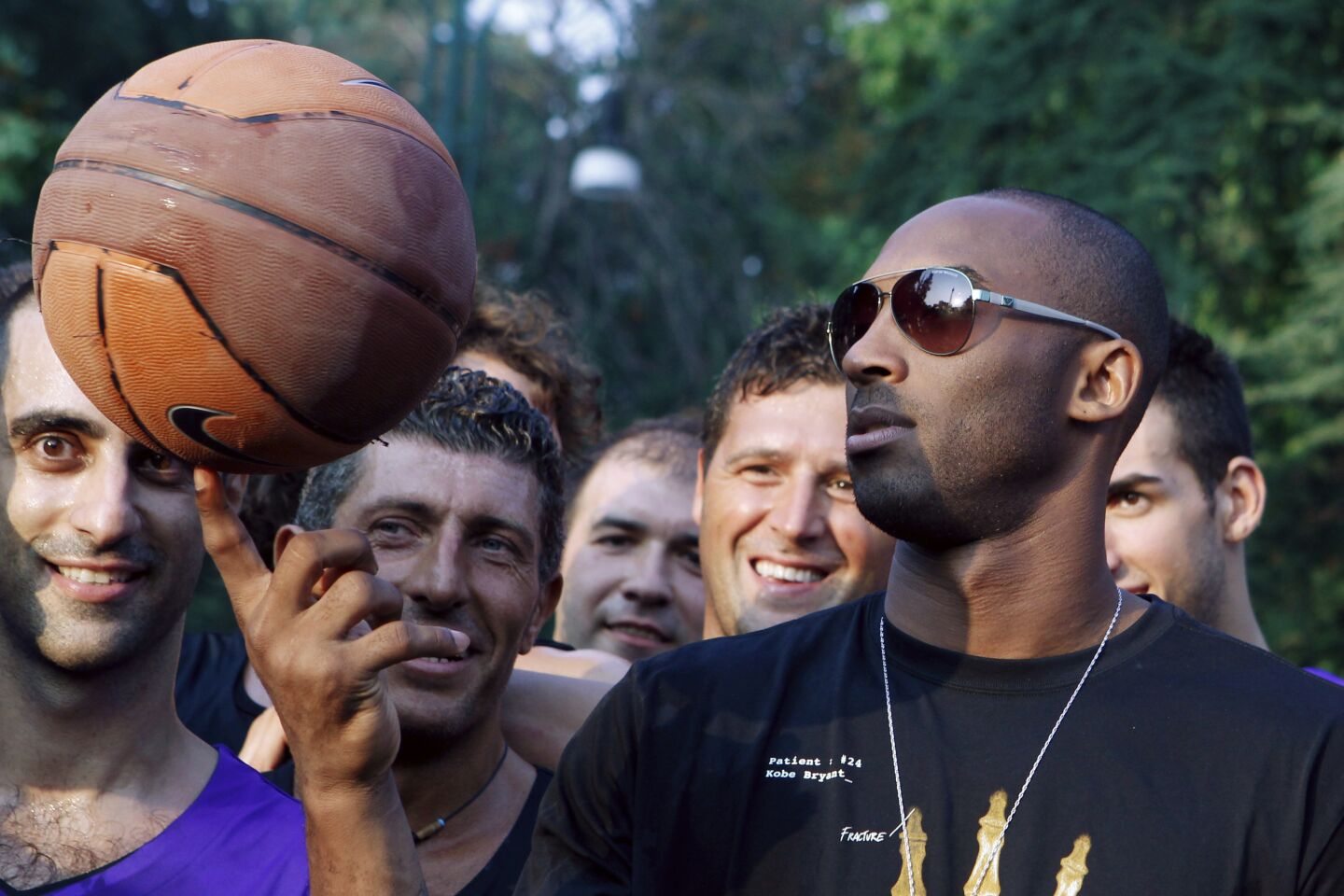 Kobe Bryant balances a basketball on his finger for a crowd in Milan, Italy, in 2011.