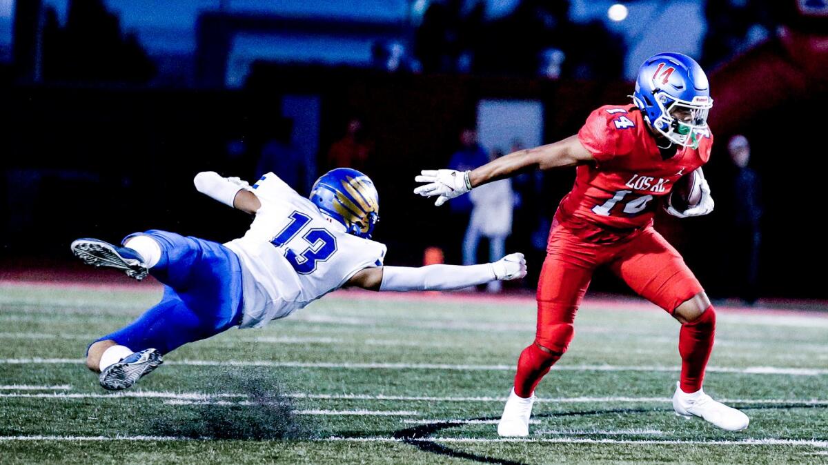 A football player dives for a player with a football.