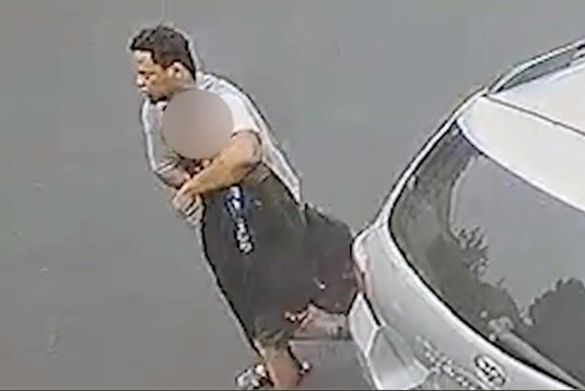 A man has his arm around a teenager on the street, next to a car