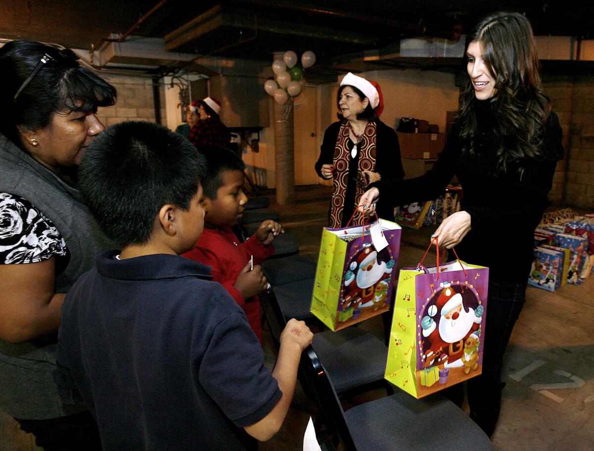 Armenian Relief Society of Western USA's Tallar Yahyayan, right, hands gifts to two local children during their annual Gift Giving Event at the company's headquarters in Glendale on December 19, 2012. Two thousand bags were expected to be given away to local children, regardless of need.The Armenian Relief Society of Western USA in Glendale, founded in 1984, is celebrating its 30th anniversary with three days of events, starting on Friday, May 2, 2014.