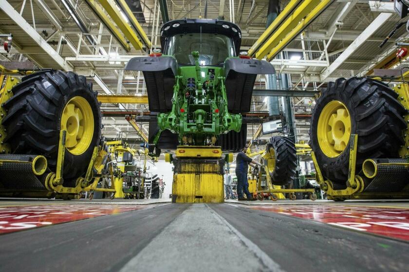 FILE - In this April 9, 2019, wheels are attach as workers assemble a tractor at John Deere's Waterloo, Iowa assembly plant. John Deere reports earnings Wednesday, April 24. (Zach Boyden-Holmes/Telegraph Herald via AP, File)