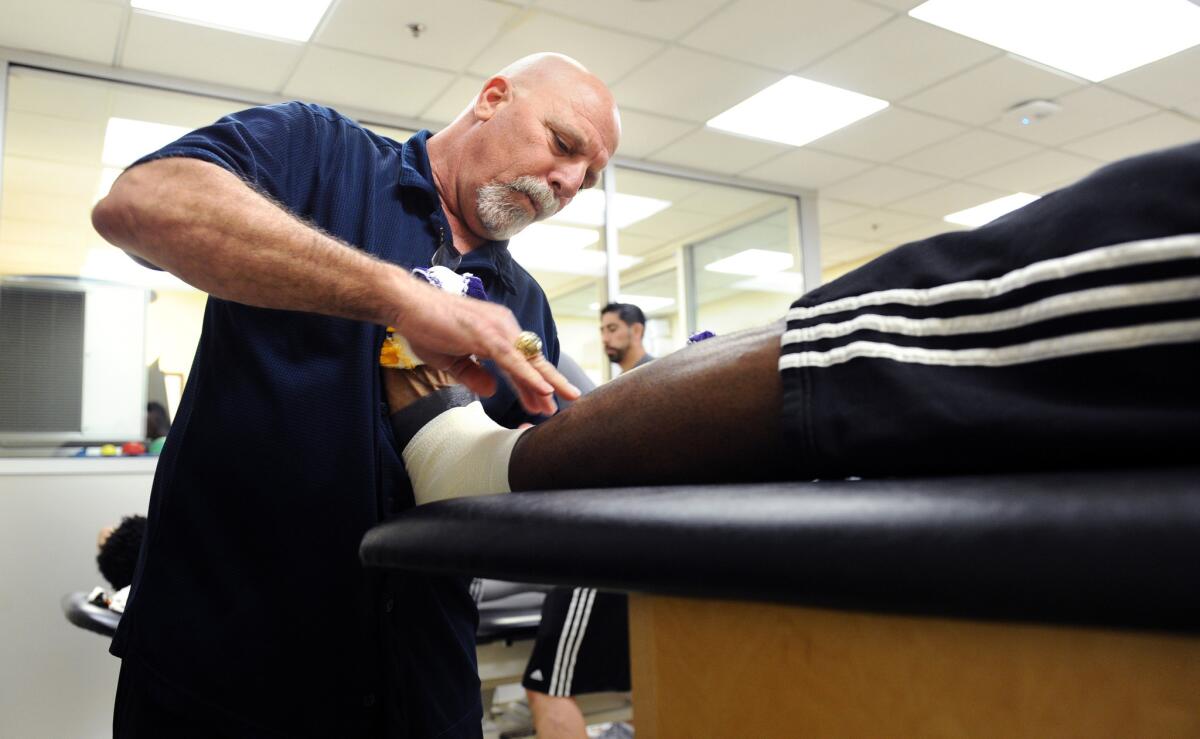 Lakers trainer Gary Vitti wraps a foot of a Lakers player in the locker room at the Staples Center.