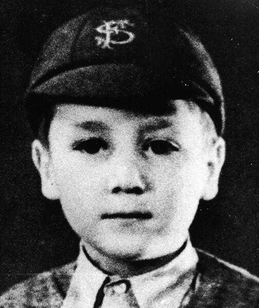 A young John Lennon wearing a school uniform and cap in 1948.
