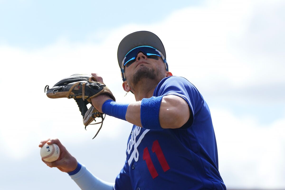 Los Angeles Dodgers shortstop Miguel Rojas looks to toss a baseball into the crowd during the first inning.