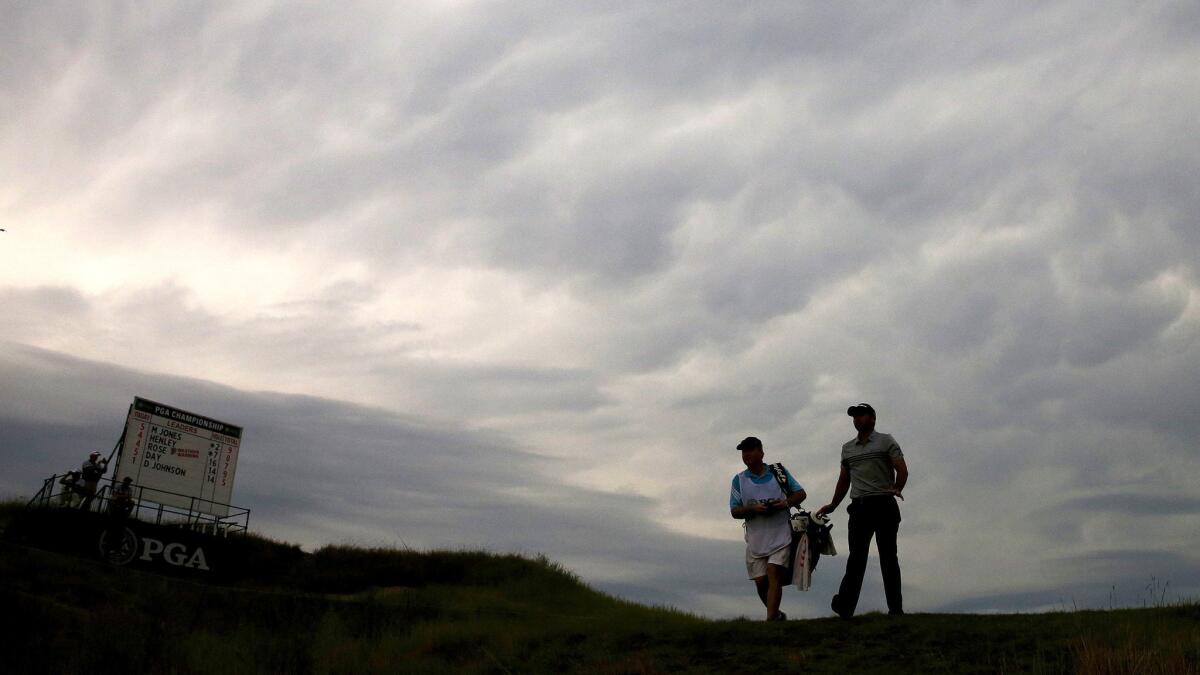 Jason Day and his caddie walks off the 15th tee under ominous skies during the second round of the PGA Championship on Friday at Whistling Straits.