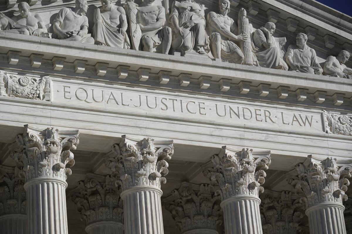 An ornate building with four massive columns and above them the words “Equal Justice Under Law.”