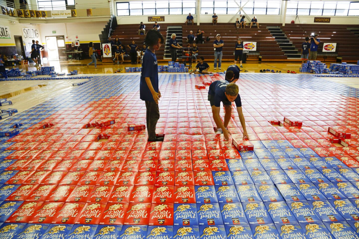Taj Gillin (left) and Cade Dethloff maneuver in the middle of the cardboard mosaic as he places red cereal boxes in the shape of a heart.