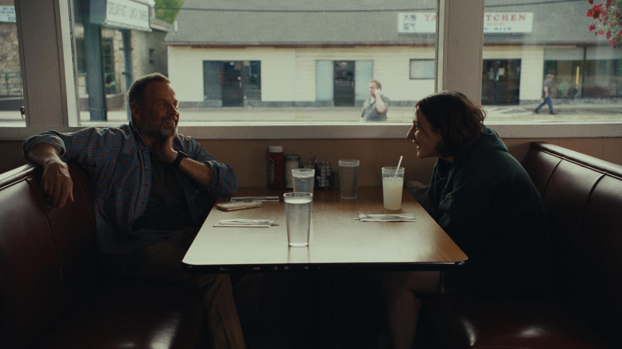 A father and his daughter are sitting at a table in a restaurant.