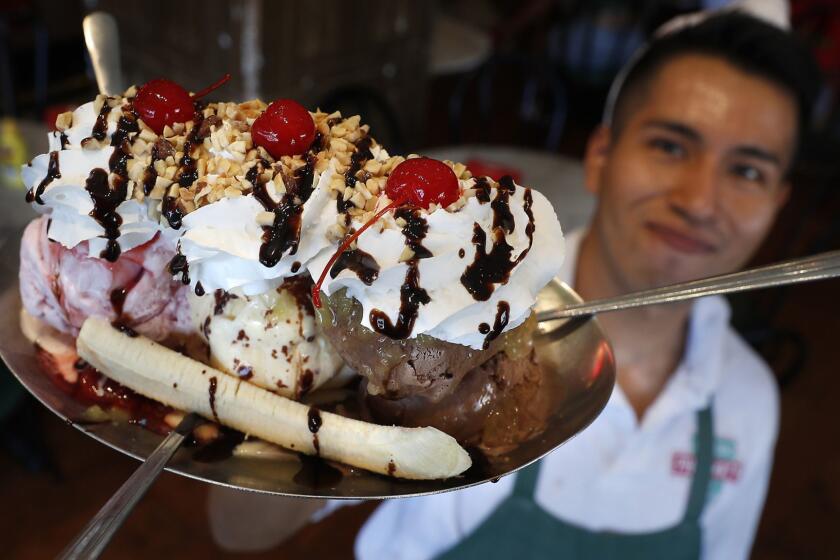 PASADENA, CA-AUGUST 4, 2018: Emplioyee Will Lopez holds up a banana split inside Fair Oaks Pharmacy in Pasadena on August 4, 2018. Pharmacy has one of the only old school soda fountains near Los Angeles. (Mel Melcon/Los Angeles Times)