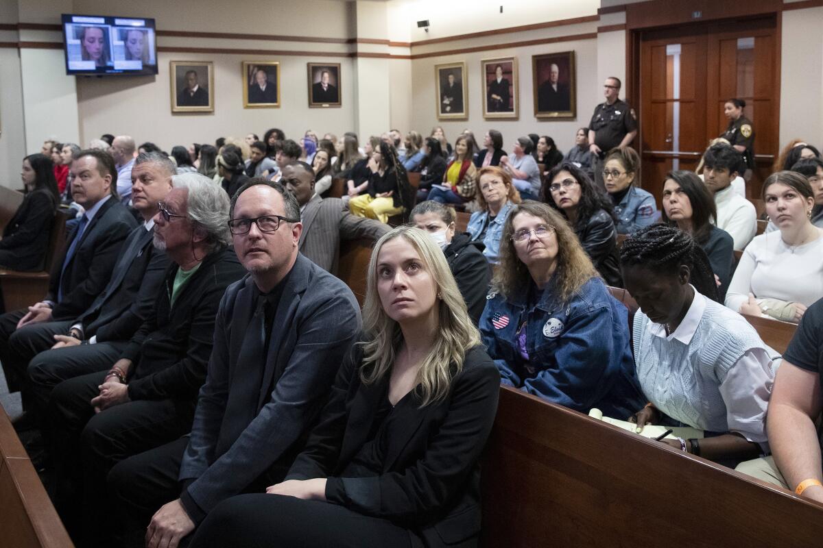 Spectators in court look up at monitors in the courtroom.