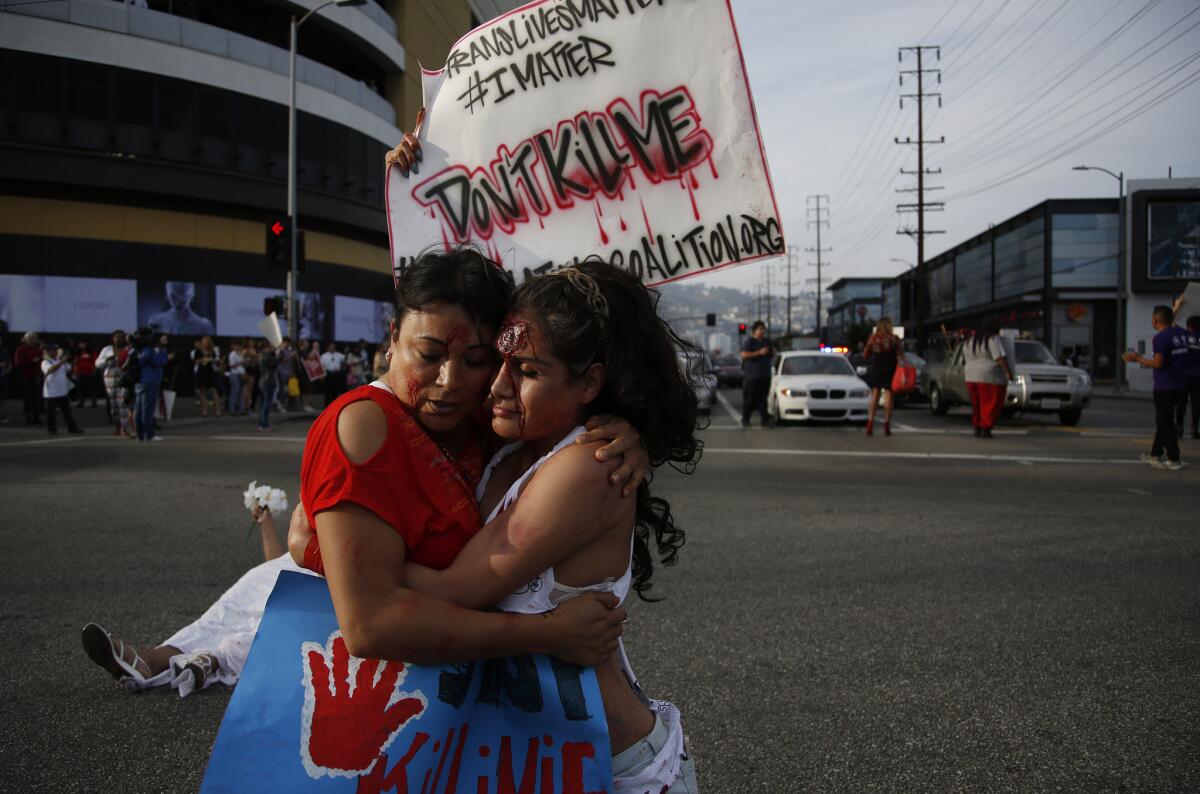 Jennicet Gutierrez, left, and Johanna Saavedra stand in the middle of the intersection at 3rd Street and La Cienega Boulevard to protest violence against transgender people.