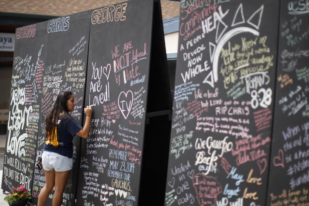 A UC Santa Barbara student adds her message to a memorial wall for victims of the Isla Vista killing rampage on May 27.