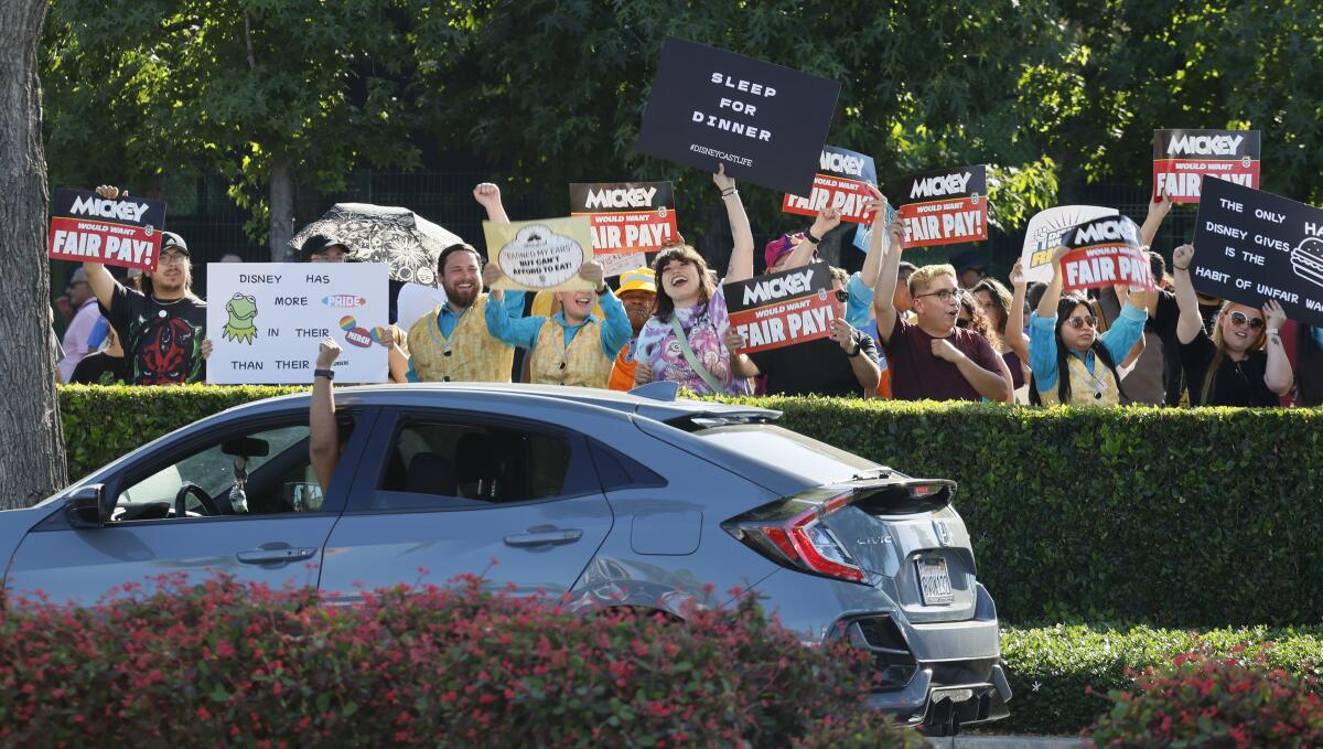 Cast members, as Disney refers to its workers, raise their fists at a Disneyland drop-off area during a July 17 rally.