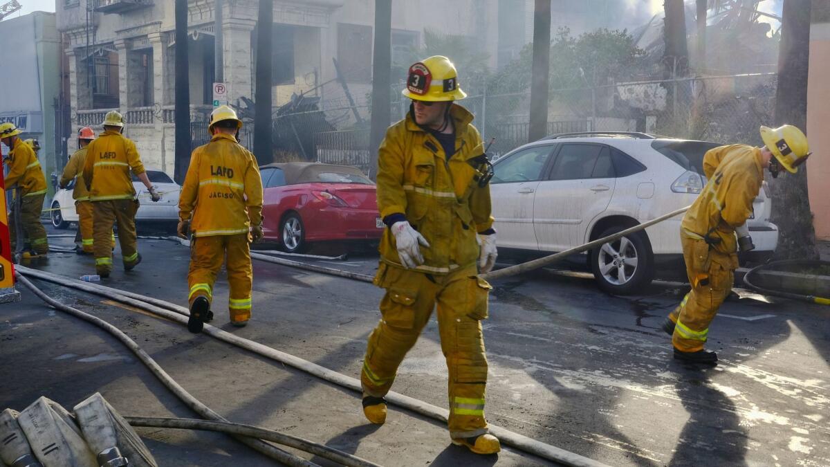 Firefighters wrap up their hoses after extinguishing a fire at a Los Angeles apartment building in April.