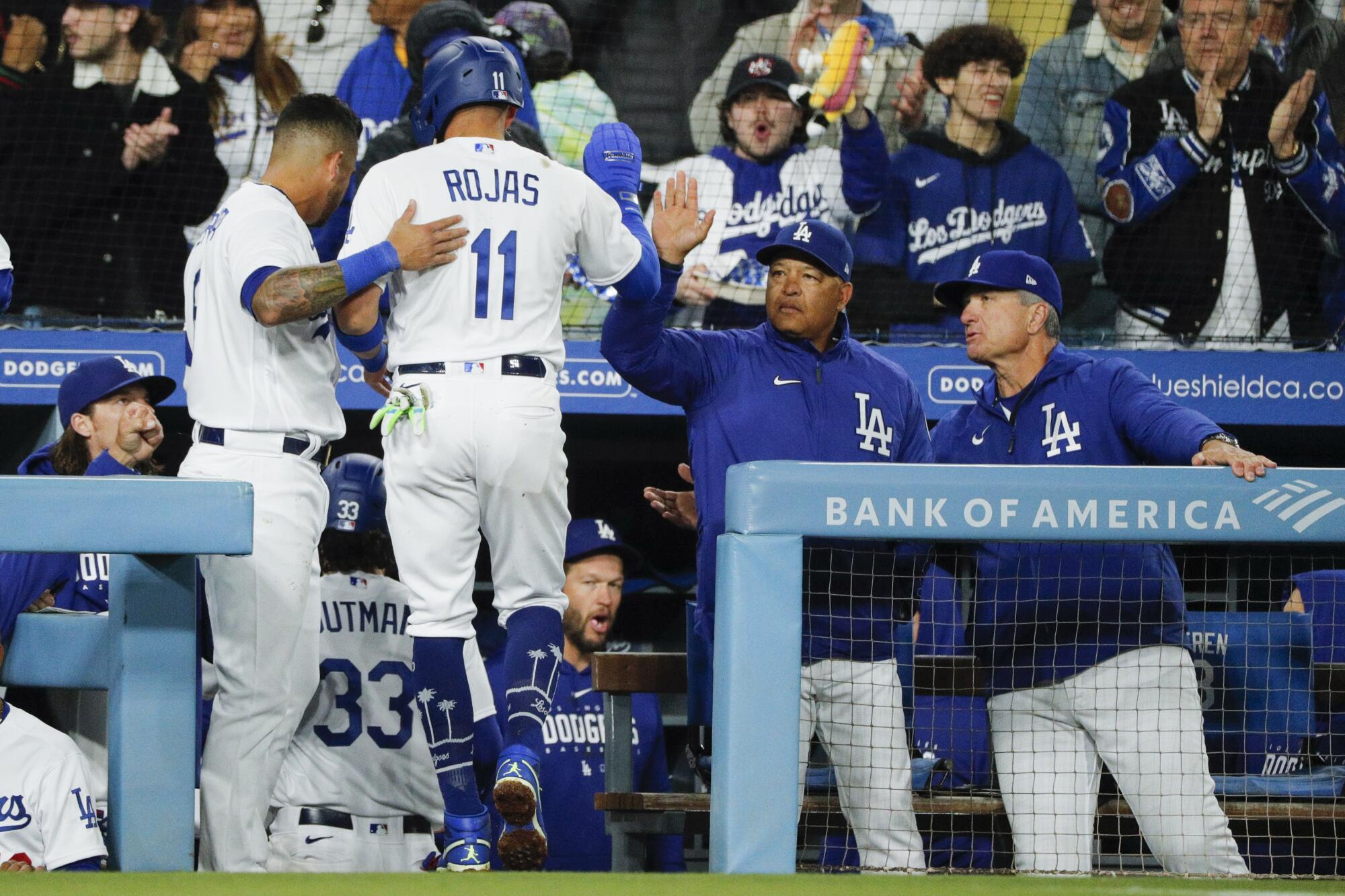 Dodgers shortstop Miguel Rojas (11) celebrates with manager Dave Roberts and teammates after scoring in the third inning.