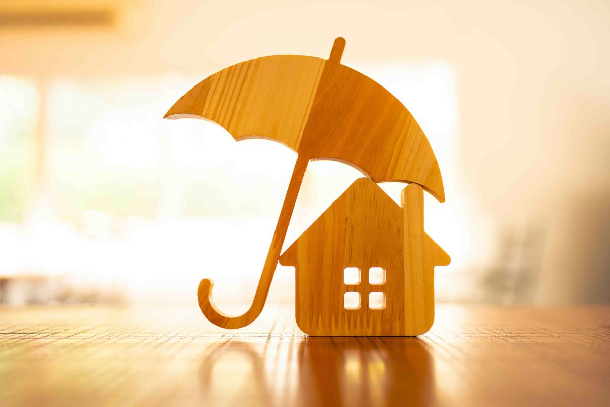 Wooden model of an umbrella with a house on a wooden table