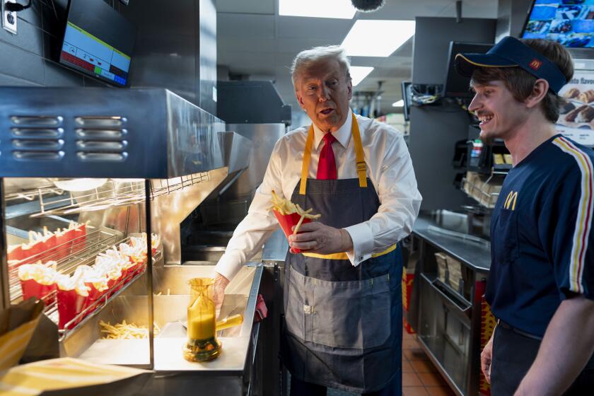 Republican presidential nominee former President Donald Trump, left, serves up french fries as an employee looks on during a campaign stop at a McDonald's in Feasterville-Trevose, Pa., Sunday, Oct. 20, 2024. (Doug Mills/The New York Times via AP, Pool)