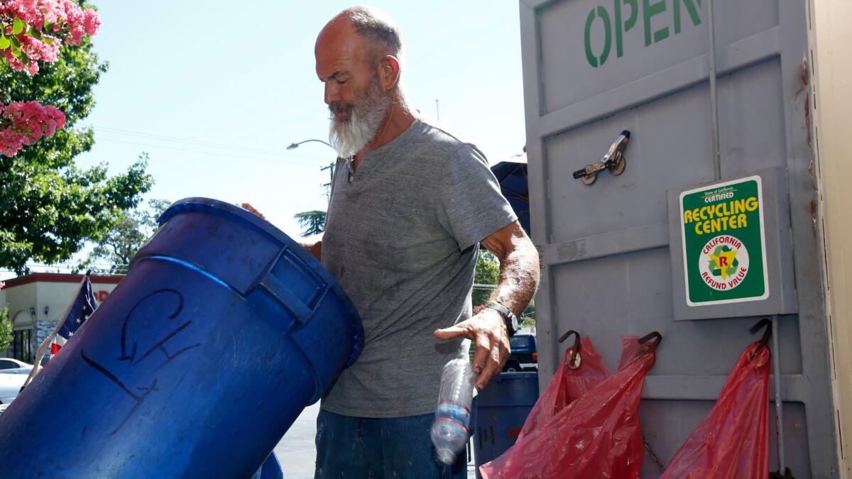 A man drops a plastic bottle into a can at a recycling center in Sacramento, Calif. on July 5, 2016.