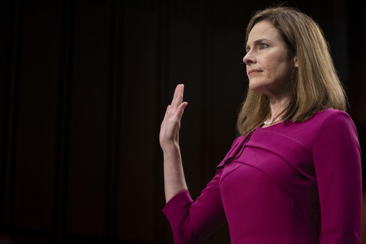 Amy Coney Barrett holds up her right hand to be sworn in before Monday's hearing. 