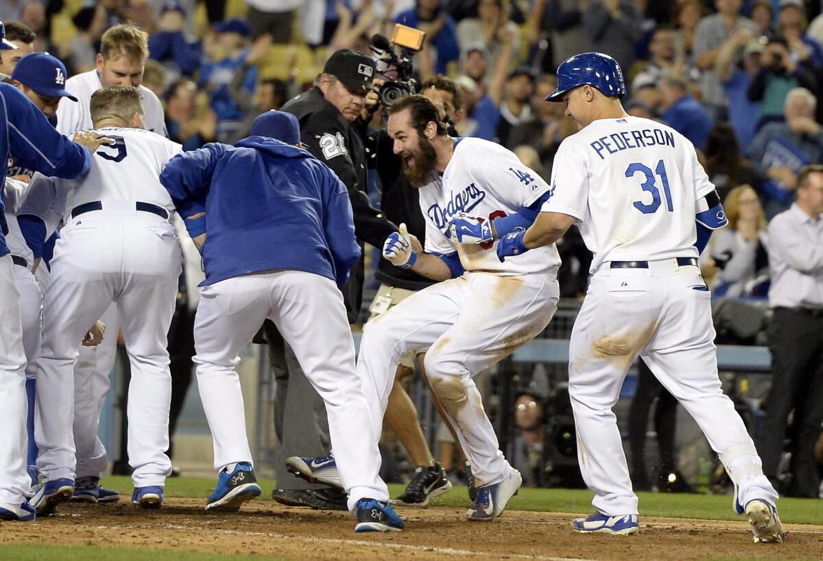 Dodgers left fielder Scott Van Slyke is mobbed by teammates after hitting the game-winning home run against the Miami Marlins on Monday night.