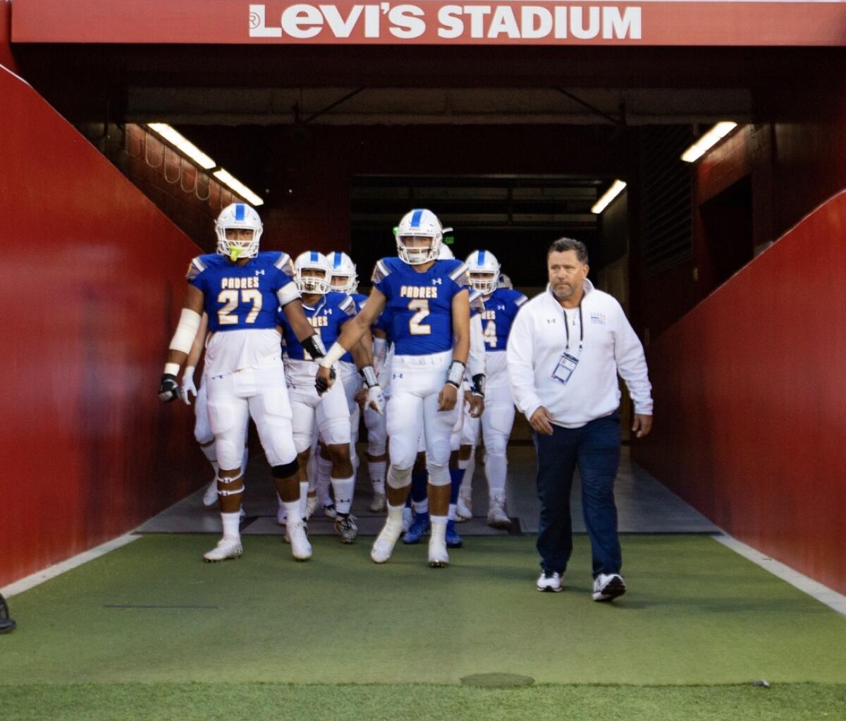 Coach Patrick Walsh and his San Mateo Serra players enter a field.