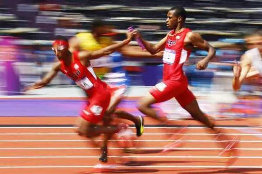 Manteo Mitchell hands the baton to U.S. teammate Josh Mance during the 1,600 relay. Mitchell broke his leg halfway through his segment of the race.