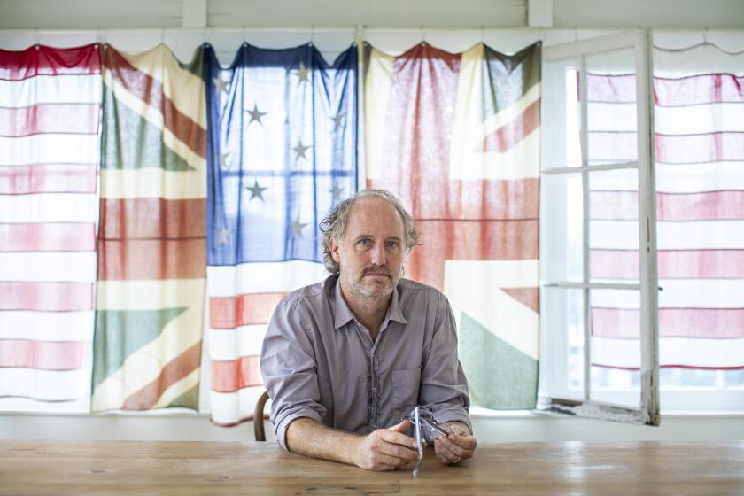 LOS ANGELES, CA - August 31: Writer and director Mike Mills is photographed in promotion of his new film, "C'mon, C'mon," at his office in the Silverlake neighborhood, of Los Angeles, CA, Tuesday, Aug. 31, 2021. The curtains behind Mills were made from pieces of old U.S. and British Union Jack flags, from a collection his father had compiled over a career as a flag designer. The new film, premiering at the Telluride Film Festival, written and directed by Mills, stars Oscar-winner Joaquin Phoenix as a radio journalist who bonds with his nephew on a cross-country road trip. (Jay L. Clendenin / Los Angeles Times)
