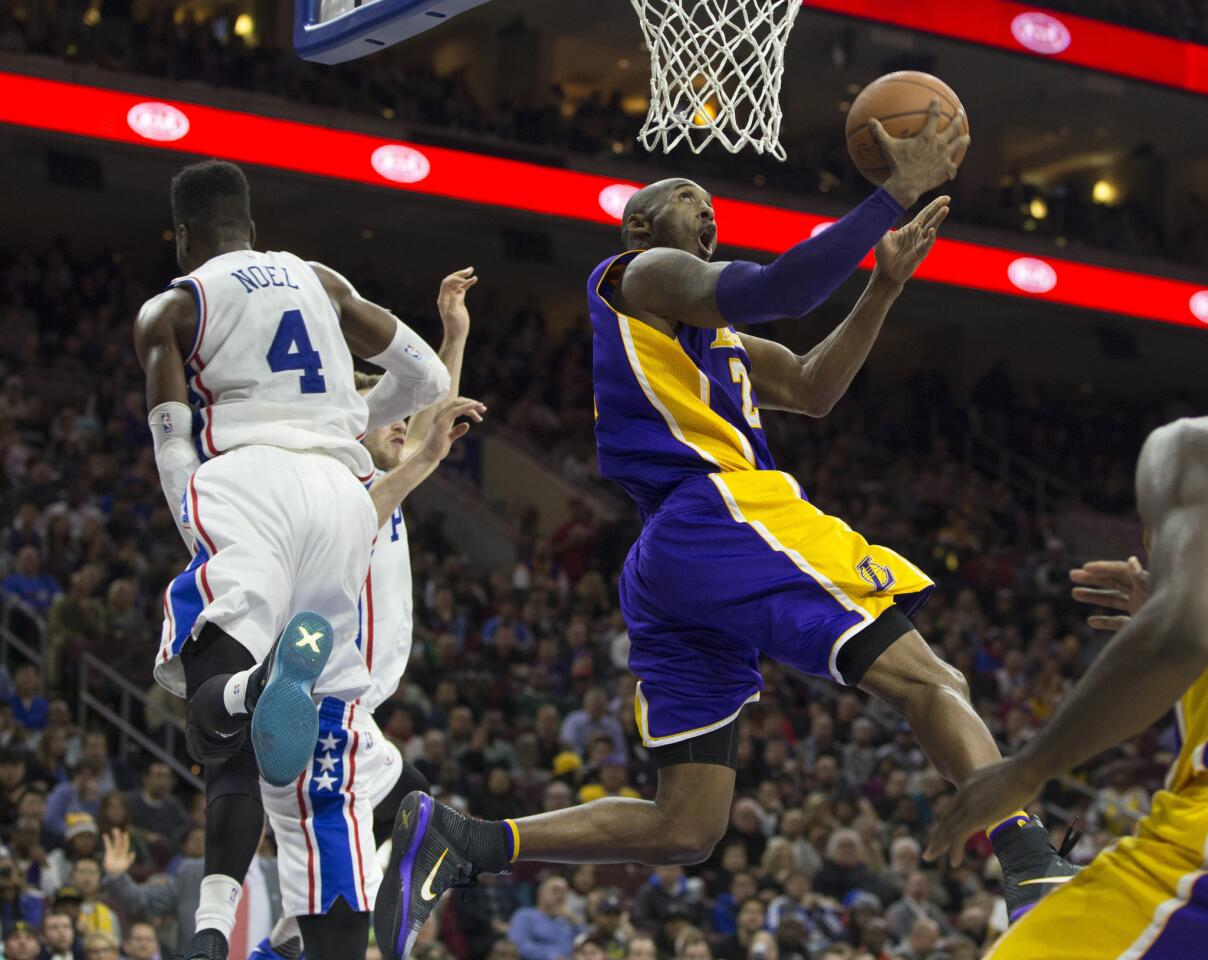 Lakers forward Kobe Bryant goes by a leaping Nerlens Noel and makes a reverse layup.