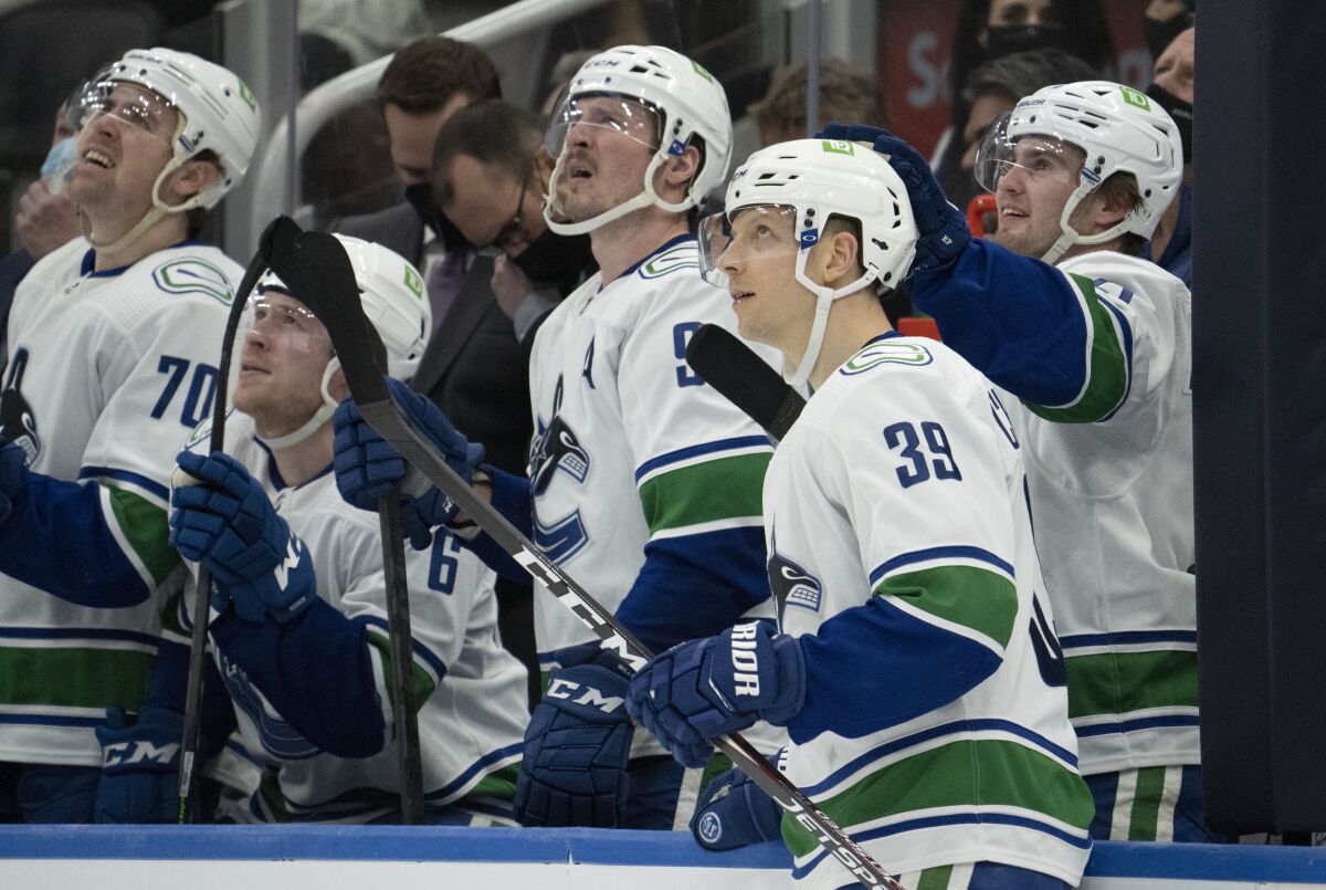 Vancouver Canucks right wing Alex Chiasson (39) is congratulated by Nils Hoglander, right, for his goal as against the Toronto Maple Leafs as they and J.T. Miller (9), Brock Boeser (6) and Tanner Pearson (70) watch the video replay during the third period of an NHL hockey game Saturday, March 5, 2022, in Toronto. (Frank Gunn/The Canadian Press via AP)