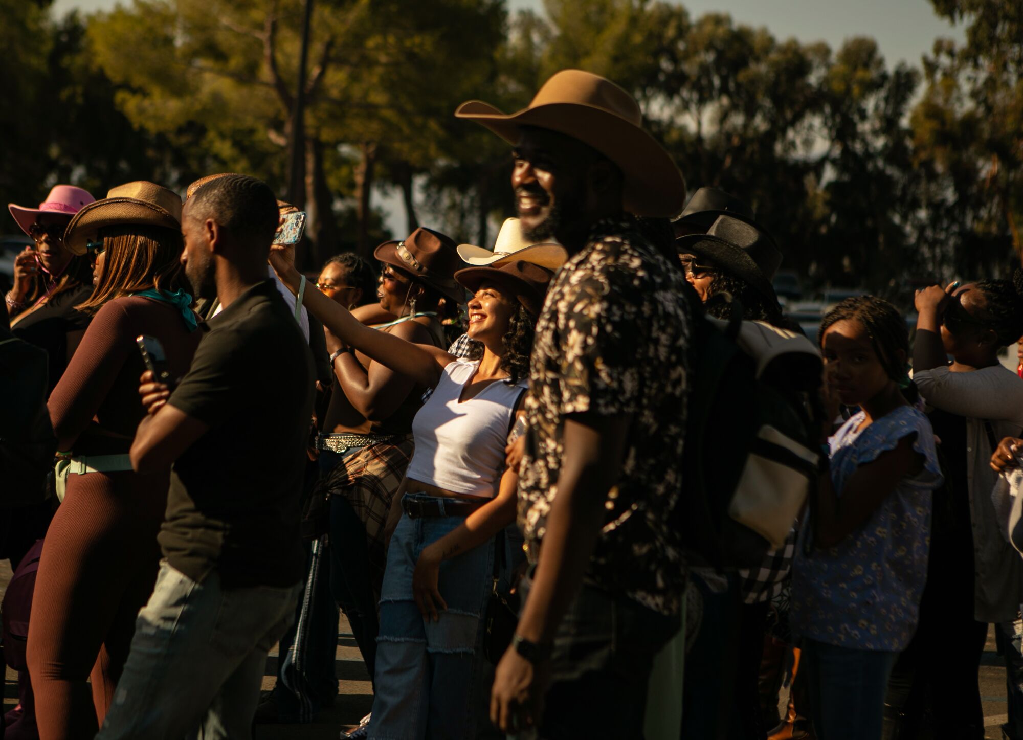 A crowd of Black people, many in cowboy hats, standing in line in the sun