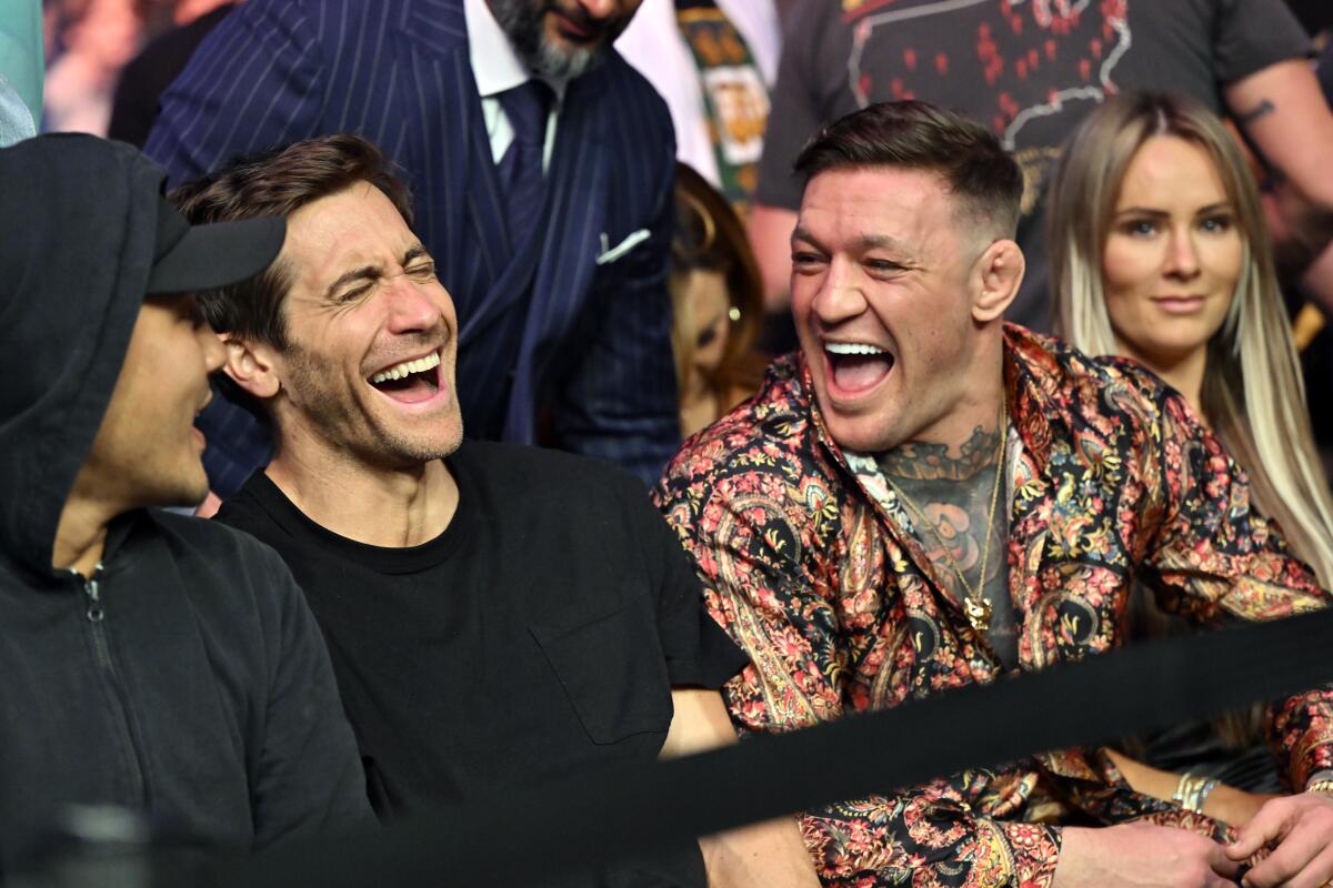 Two men laughing while sitting in a crowd