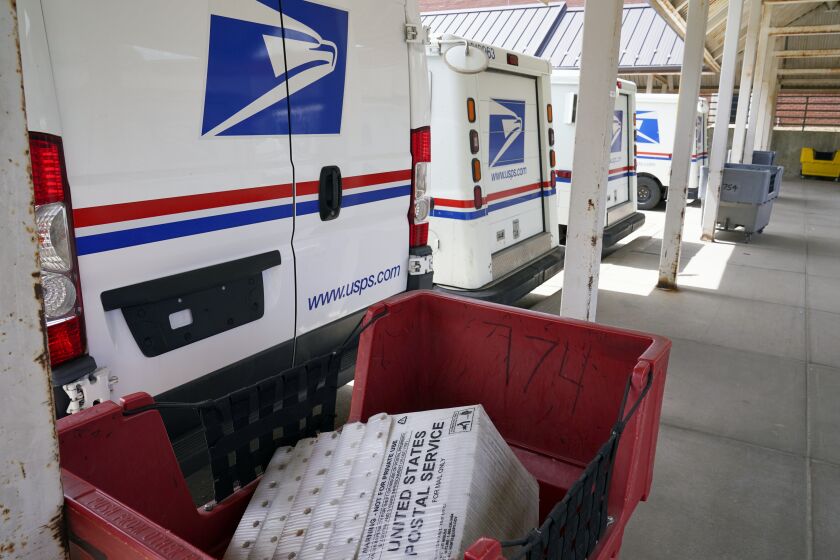 Mail delivery vehicles are parked outside a post office in Boys Town, Neb., Tuesday, Aug. 18, 2020. The Postmaster general announced Tuesday he is halting some operational changes to mail delivery that critics warned were causing widespread delays and could disrupt voting in the November election. Postmaster General Louis DeJoy said he would "suspend" his initiatives until after the election "to avoid even the appearance of impact on election mail." (AP Photo/Nati Harnik)