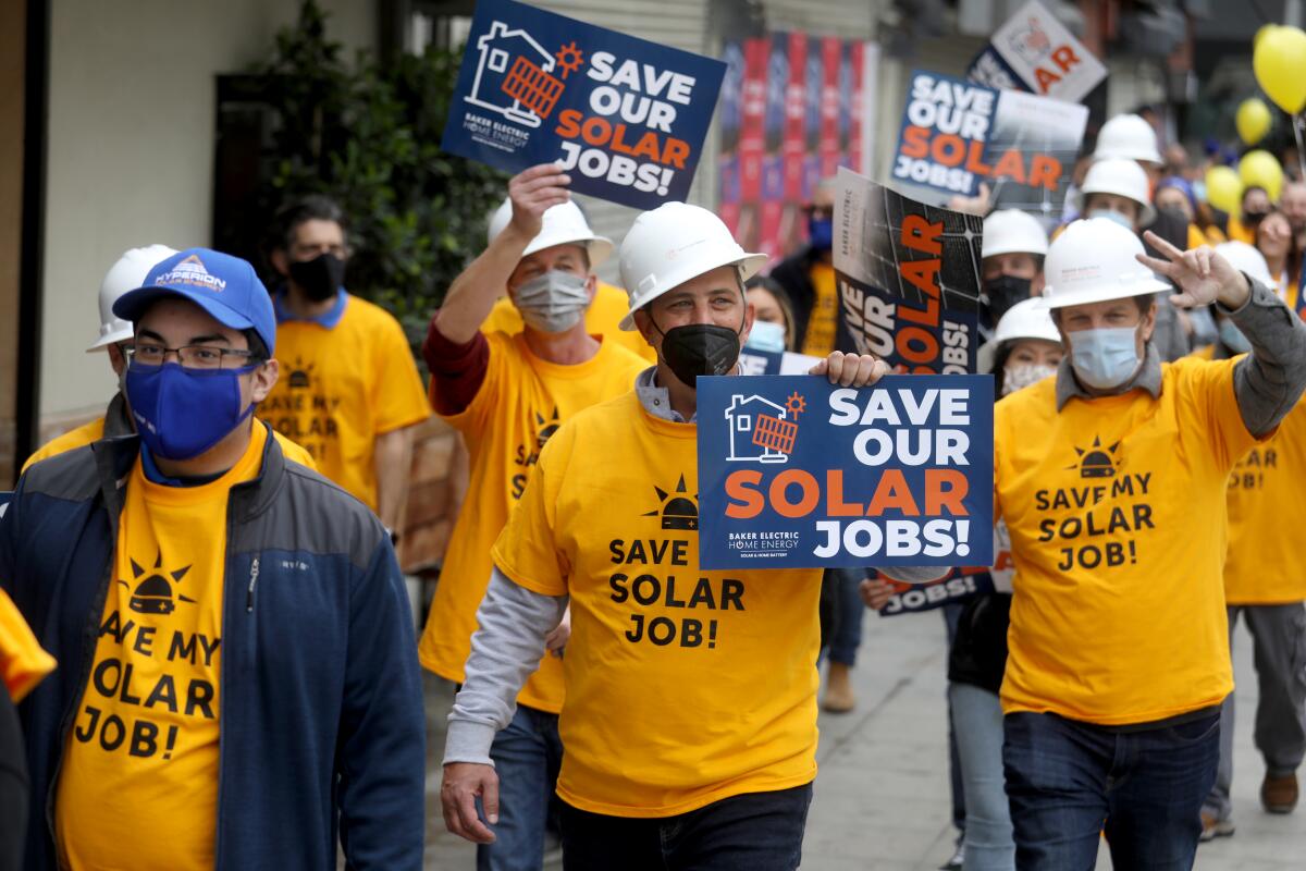 Solar industry employees march through downtown Los Angeles as part of a "Save Our Solar Jobs" rally in 2022.