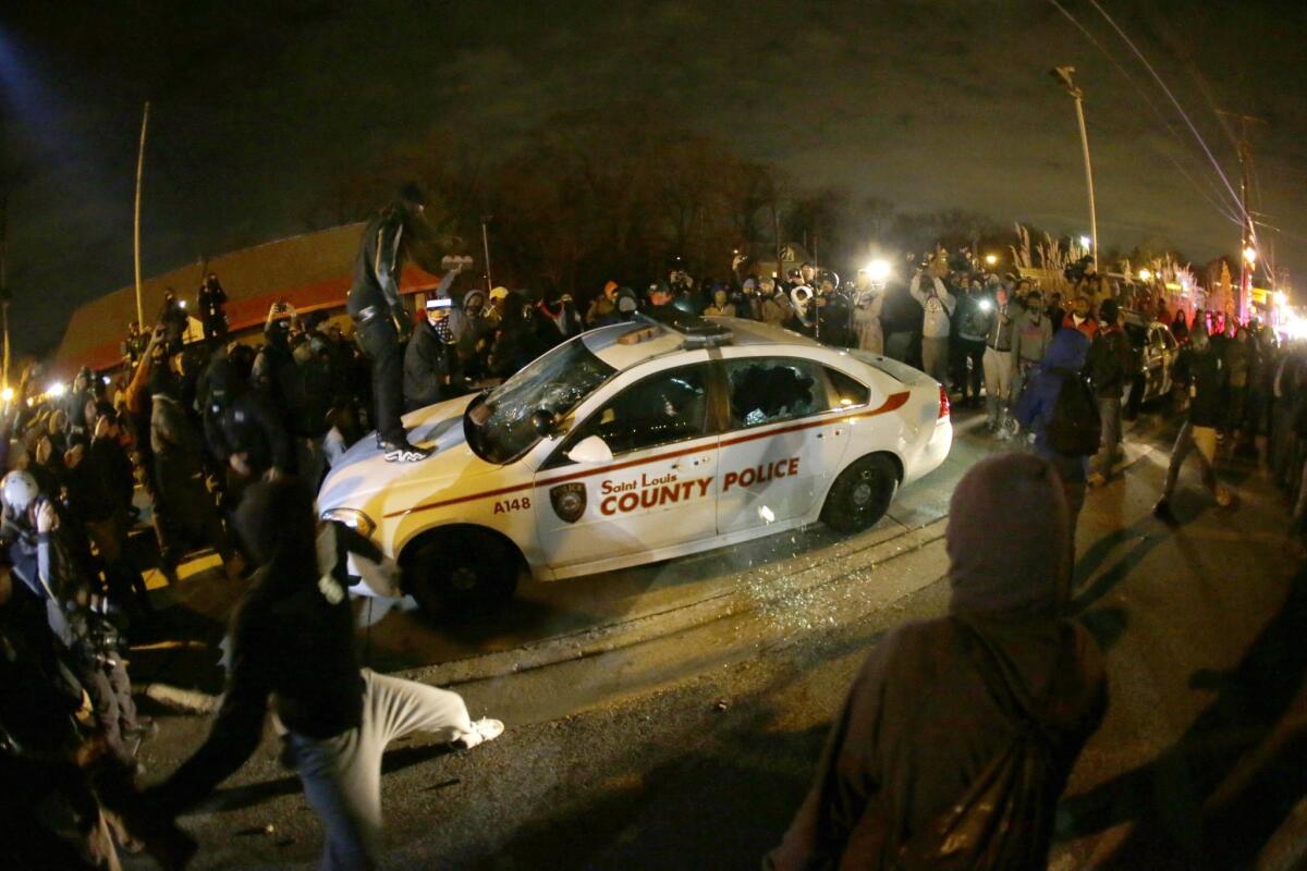 A protester squirts lighter fluid on a vandalized police car in Ferguson, Mo., on Nov. 24.