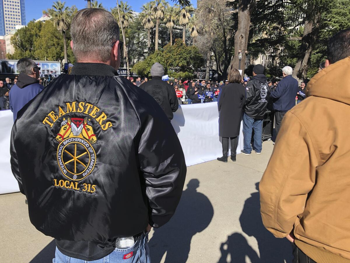 A man in a Teamsters jacket joins a rally at the California Capitol.