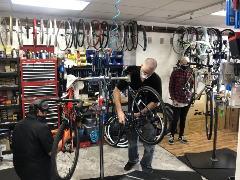 Dan Zapkowski (center), owner of Pacific Beach Bikes, works in his retail shop on Grand Avenue.