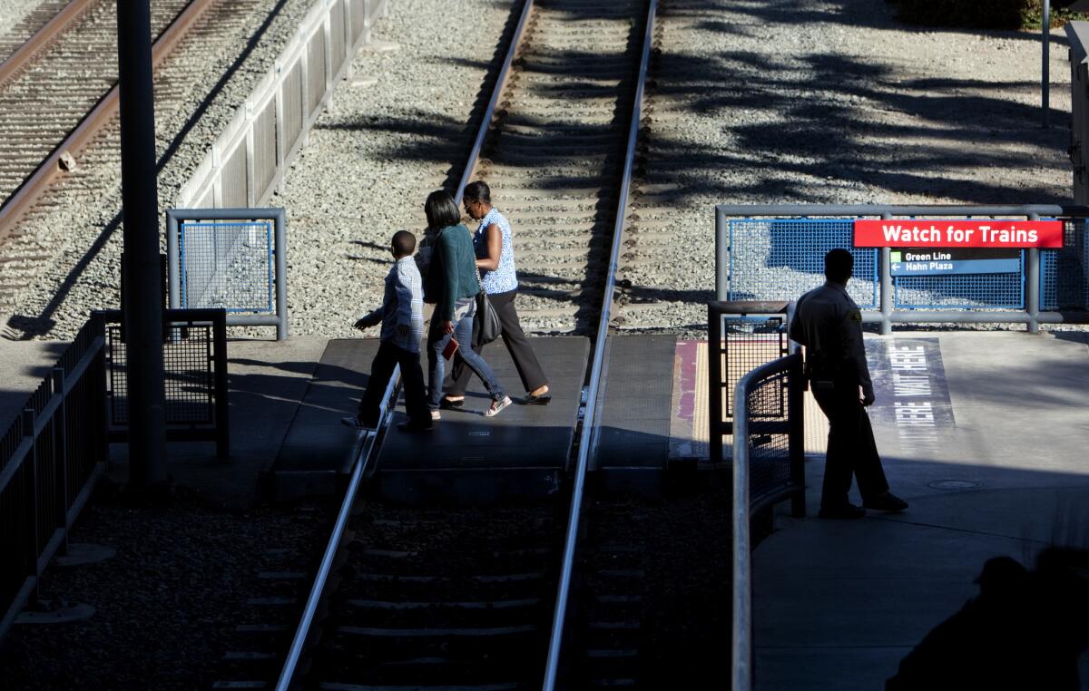 Pedestrians cross the tracks at a Metro Blue Line station. A man was struck and killed Friday evening by a Blue Line train in South L.A., disrupting service during rush hour and causing delays.