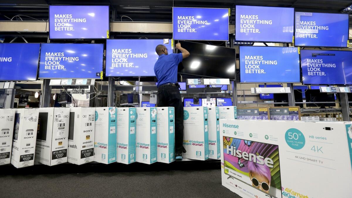 An employee adjusts a television display at a Best Buy store in Cary, N.C.