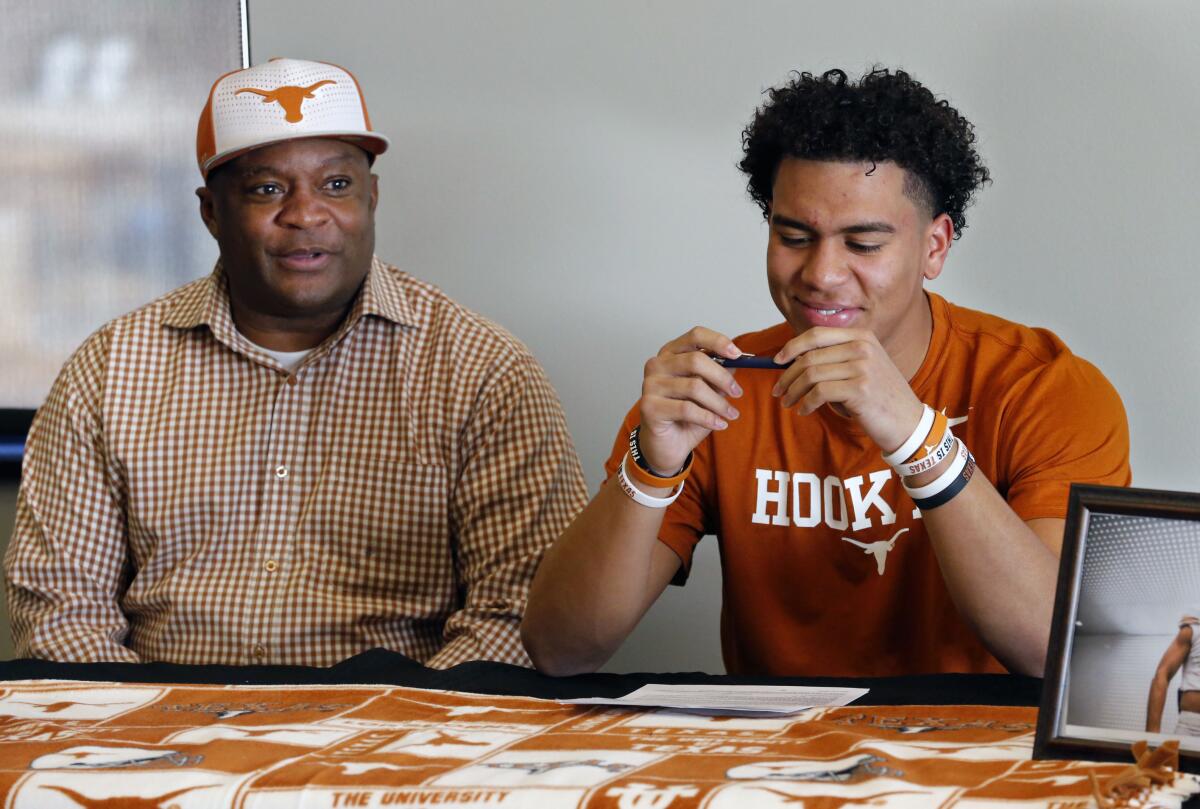 FILE - Former Oklahoma quarterback Charles Thompson, left, looks on as his son, Newcastle quarterback Casey Thompson, prepares to sign a letter of intent to play football for the University of Texas in Newcastle, Okla., Wednesday, Dec. 20, 2017. Oklahoma quarterback Charles Thompson led the Sooners to a win over Nebraska in what was dubbed “Game of the Century II” back in 1987. Now, 35 years later, his son, Casey, will be Nebraska’s quarterback against the Sooners. (Steve Sisney/The Oklahoman via AP, File)