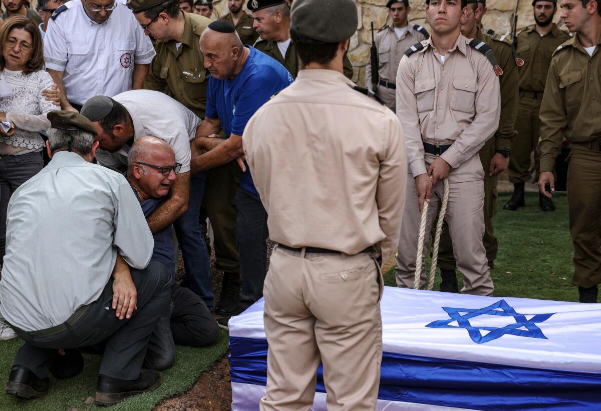 People stand near a coffin draped with an Israeli flag.