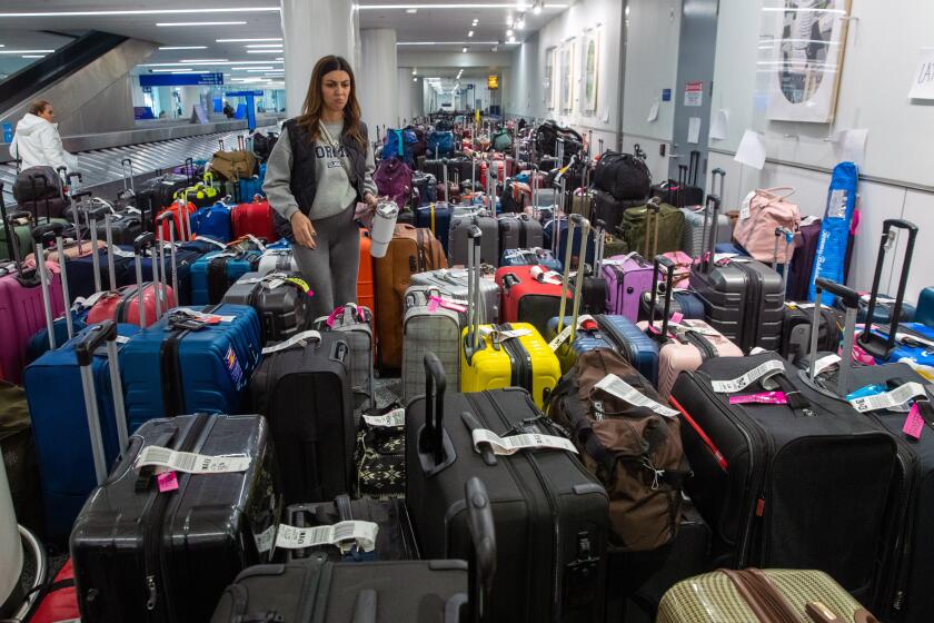 Los Angeles, CA - December 27: Amanda Gevorgyan looks for her luggage among hundreds bags from Southwest flight cancellations, gathered at baggage claim at LAX Southwest Terminal 1 on Tuesday, Dec. 27, 2022 in Los Angeles, CA. (Irfan Khan / Los Angeles Times)